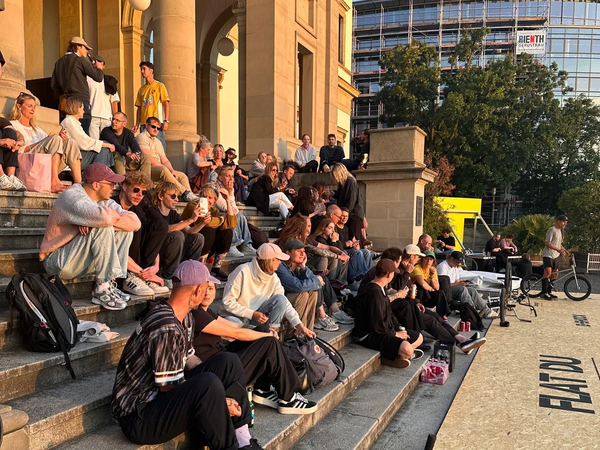 Visitors sitting in the evening sun on the steps in front of the StadtPalais