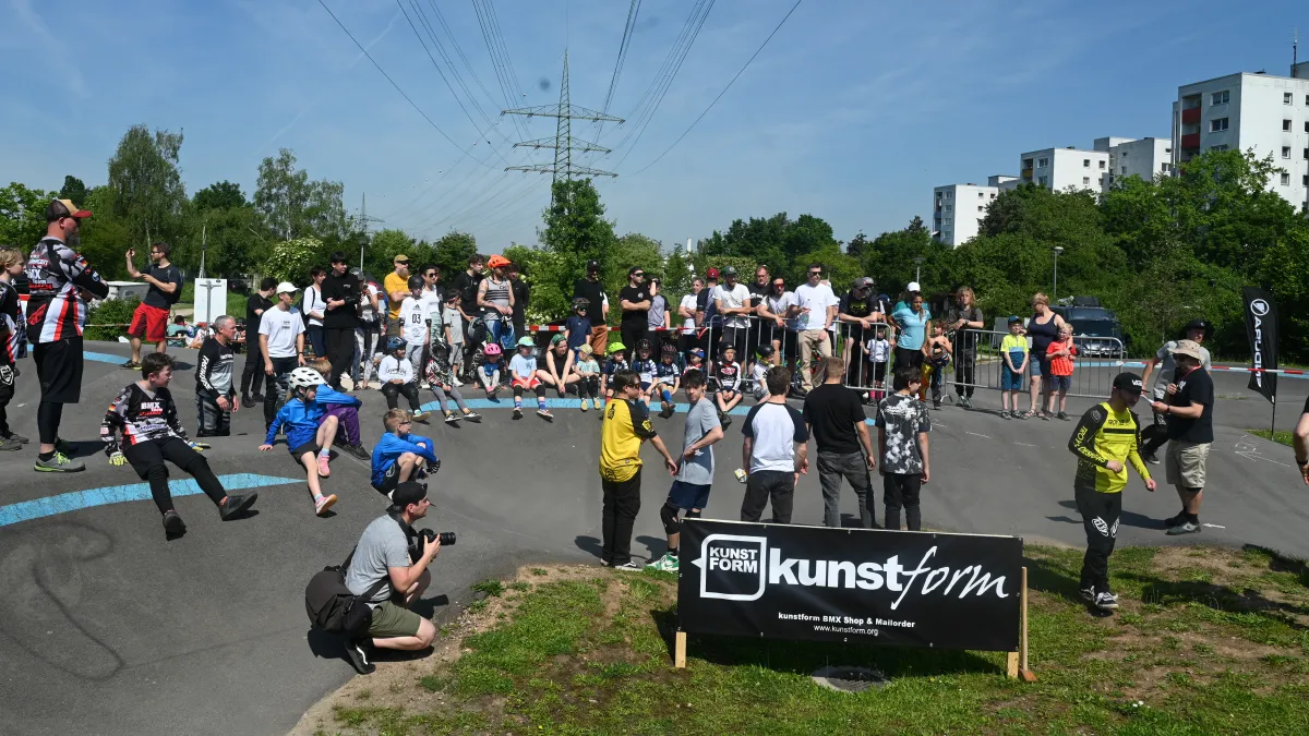 Pumptrack Rennen mit vielen Zuschauern, im Vordergrund ein kunstform Banner