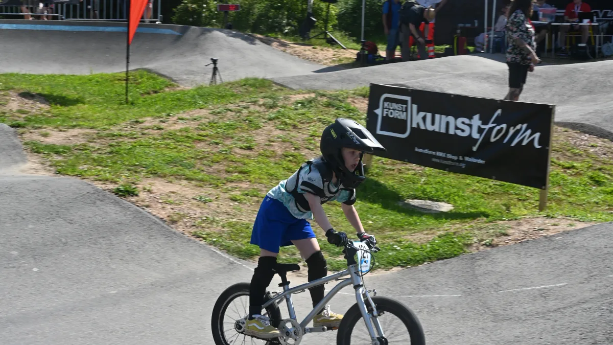Junger Fahrer auf dem Pumptrack, dahinter das kunstform Banner